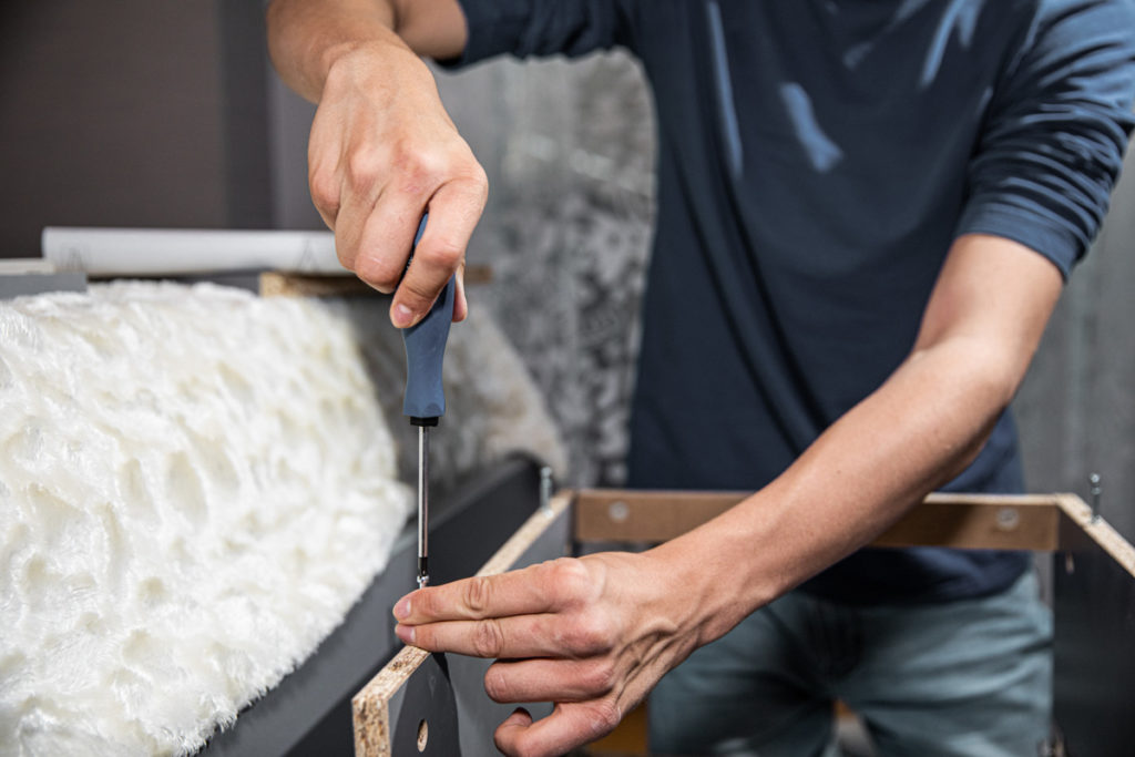 Teenager boy putting furniture together at home, using screwdriver